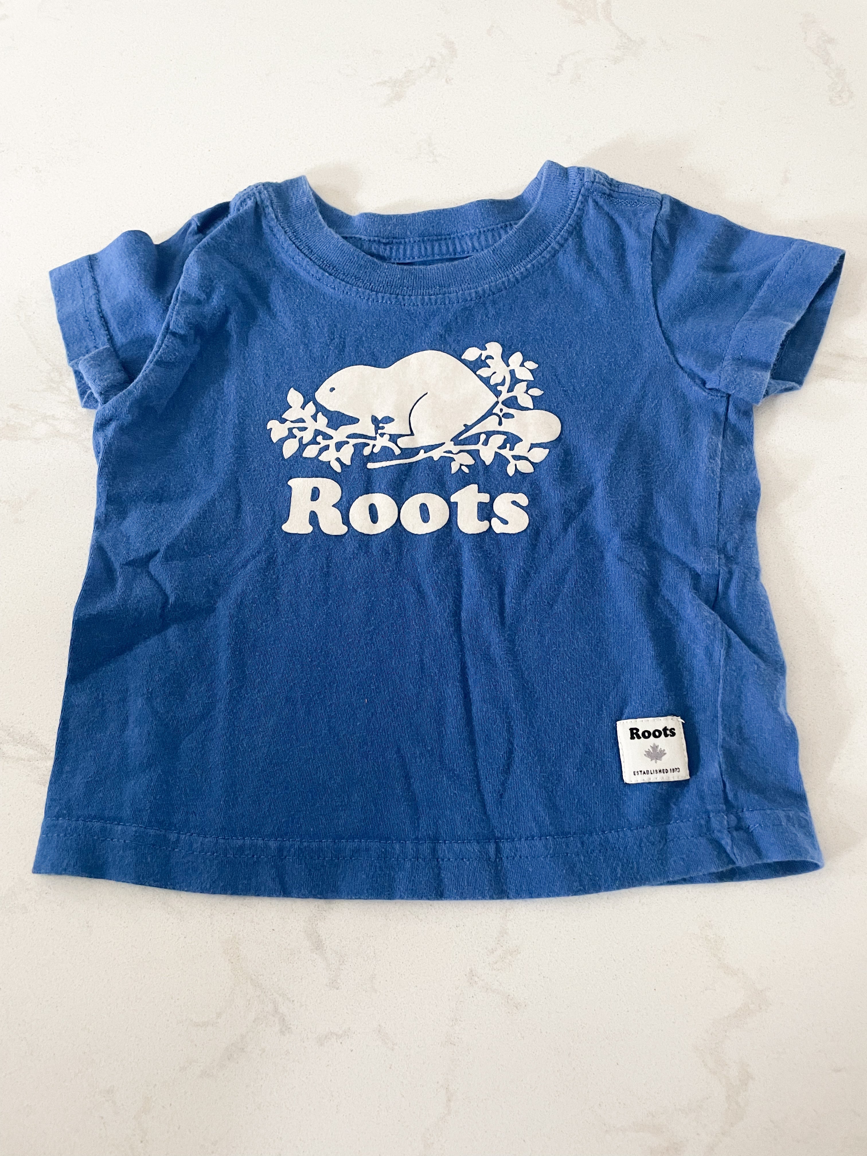 Roots- 3-6 months- medium blue t shirt with white logo