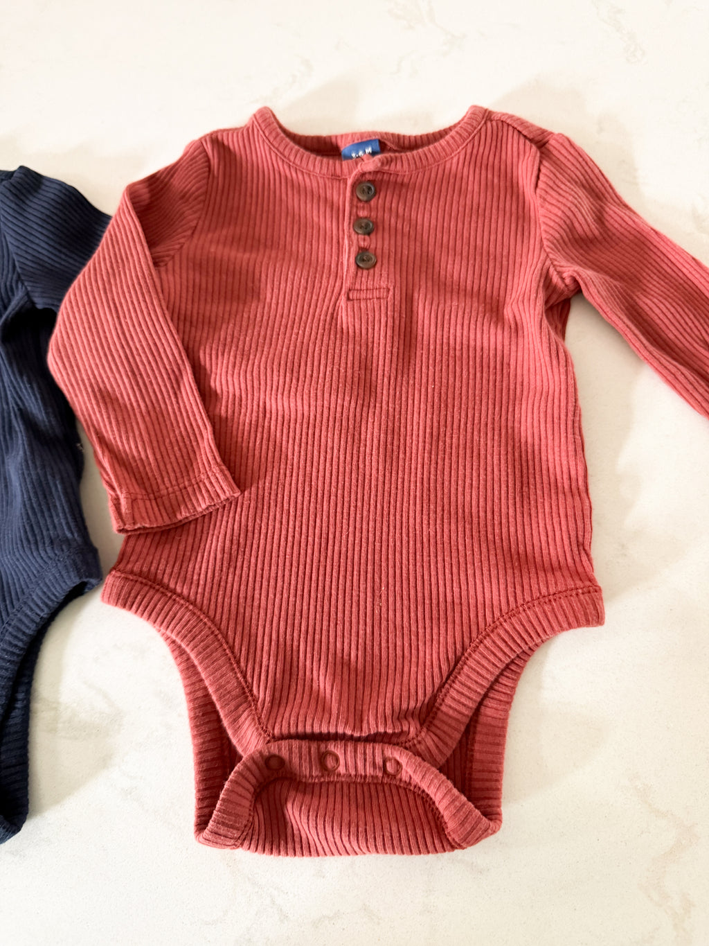 Old Navy- 3-6m- VGUC- two long sleeve ribbed bodysuits, navy and terracotta colouring