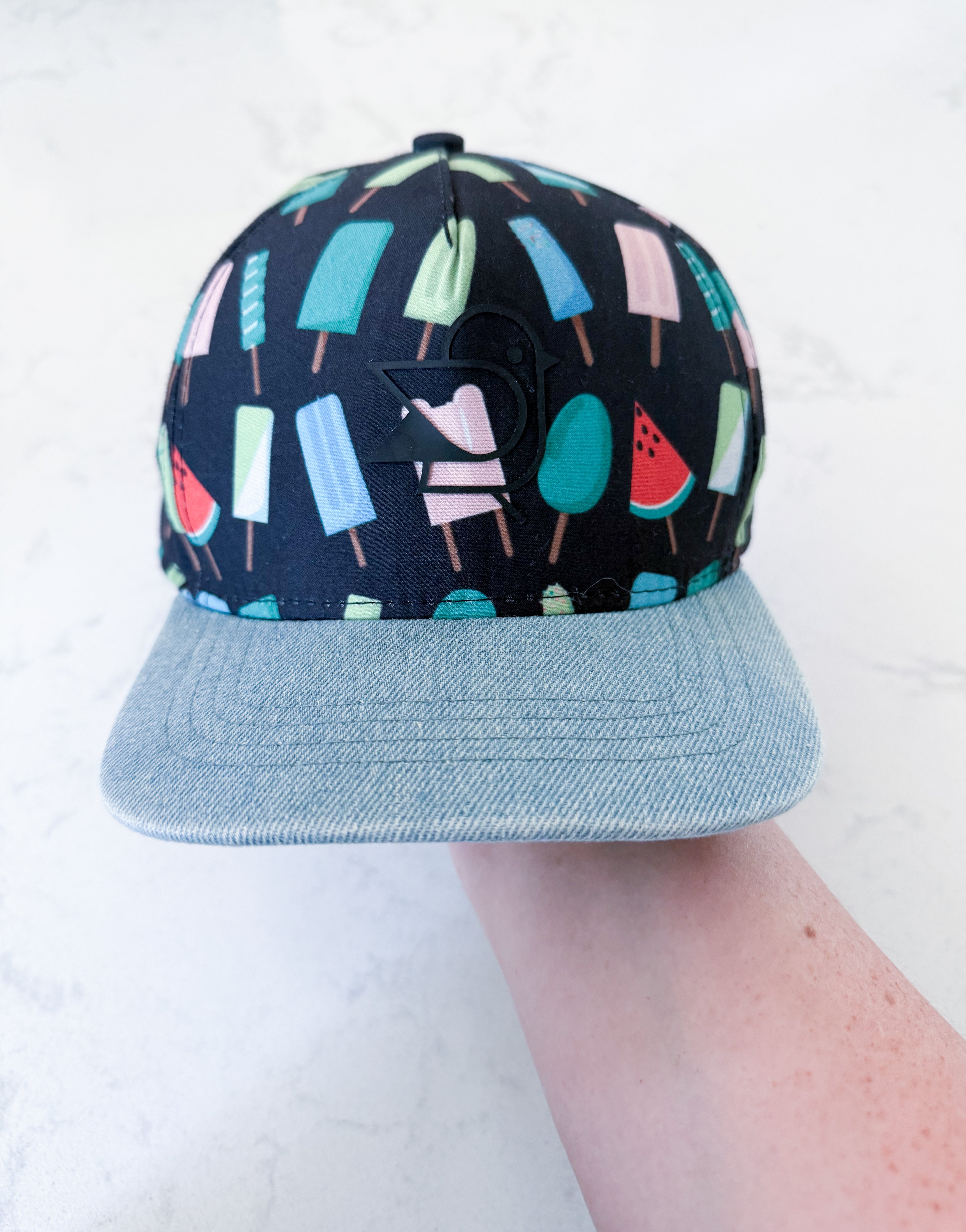 Birdz- 0-24m- GUC- black ball cap with blue brim and popsicle graphic