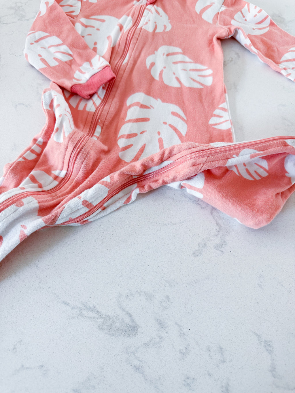 Zippy Jamz- 9-12m- PLAY- orangey pink zip up jammies with white tropical leaves
