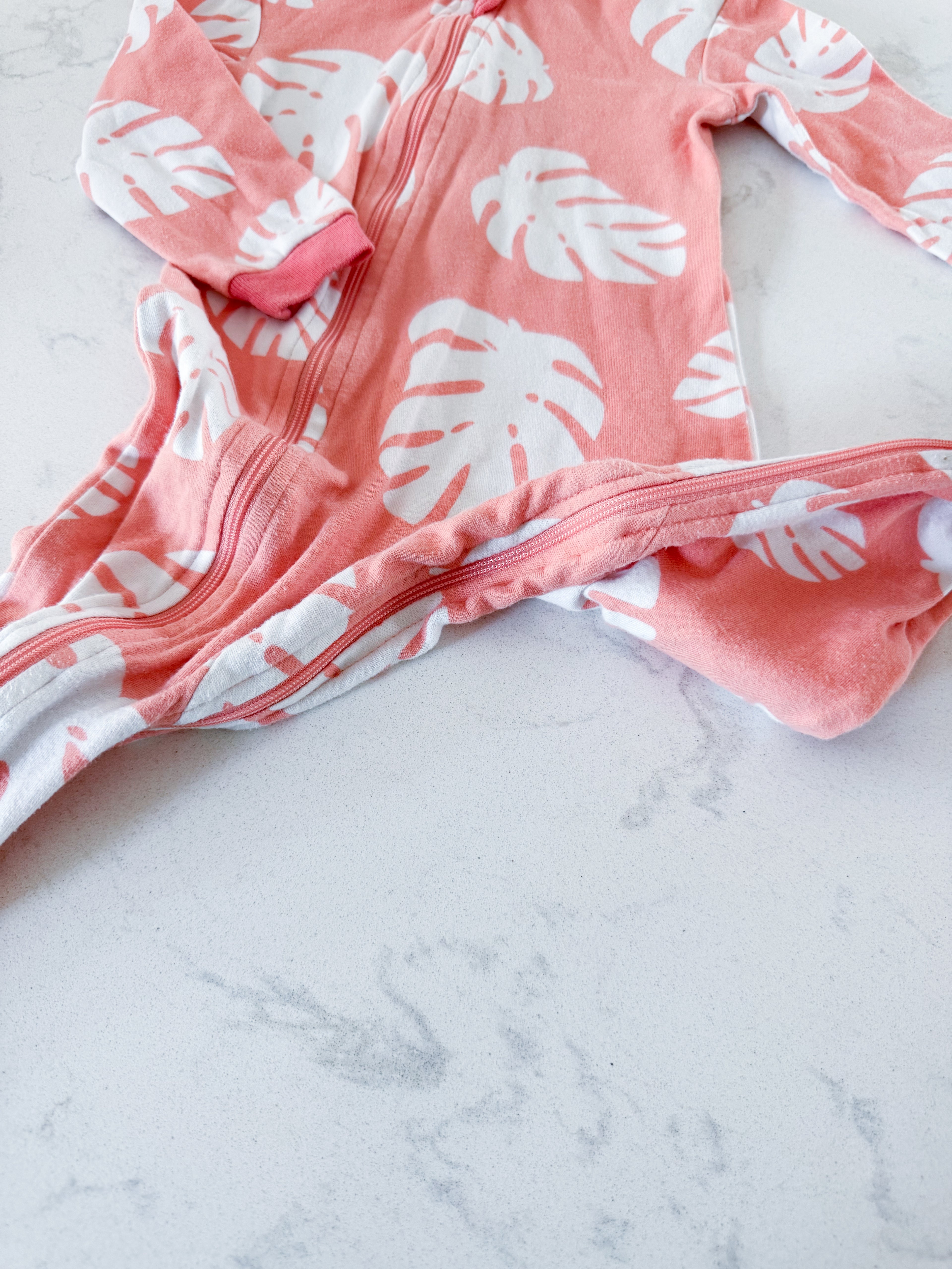 Zippy Jamz- 9-12m- PLAY- orangey pink zip up jammies with white tropical leaves