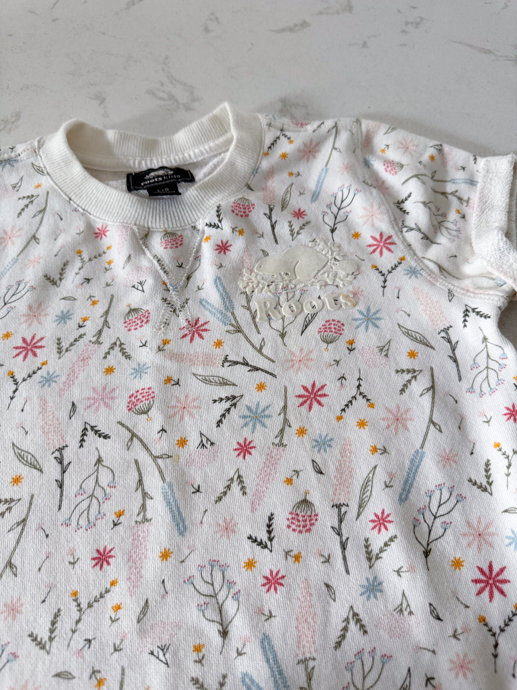 Roots- 9-10Y- VGUC- White short sleeve sweater dress with multicoloured wildflower pattern and white Roots logo