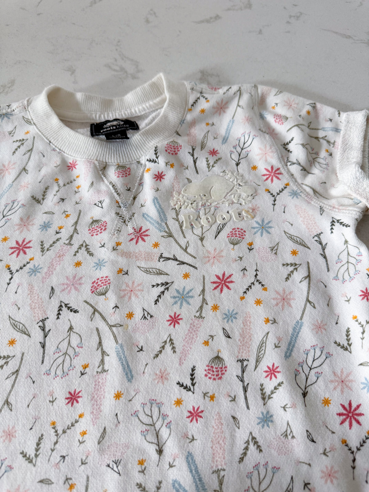 Roots- 9-10Y- VGUC- White short sleeve sweater dress with multicoloured wildflower pattern and white Roots logo