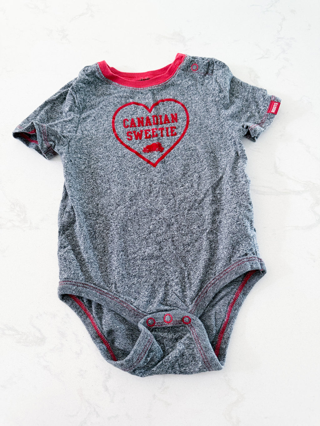 Roots- 18-24m- VGUC- grey speckled short sleeve bodysuit with Canadian sweetie on front
