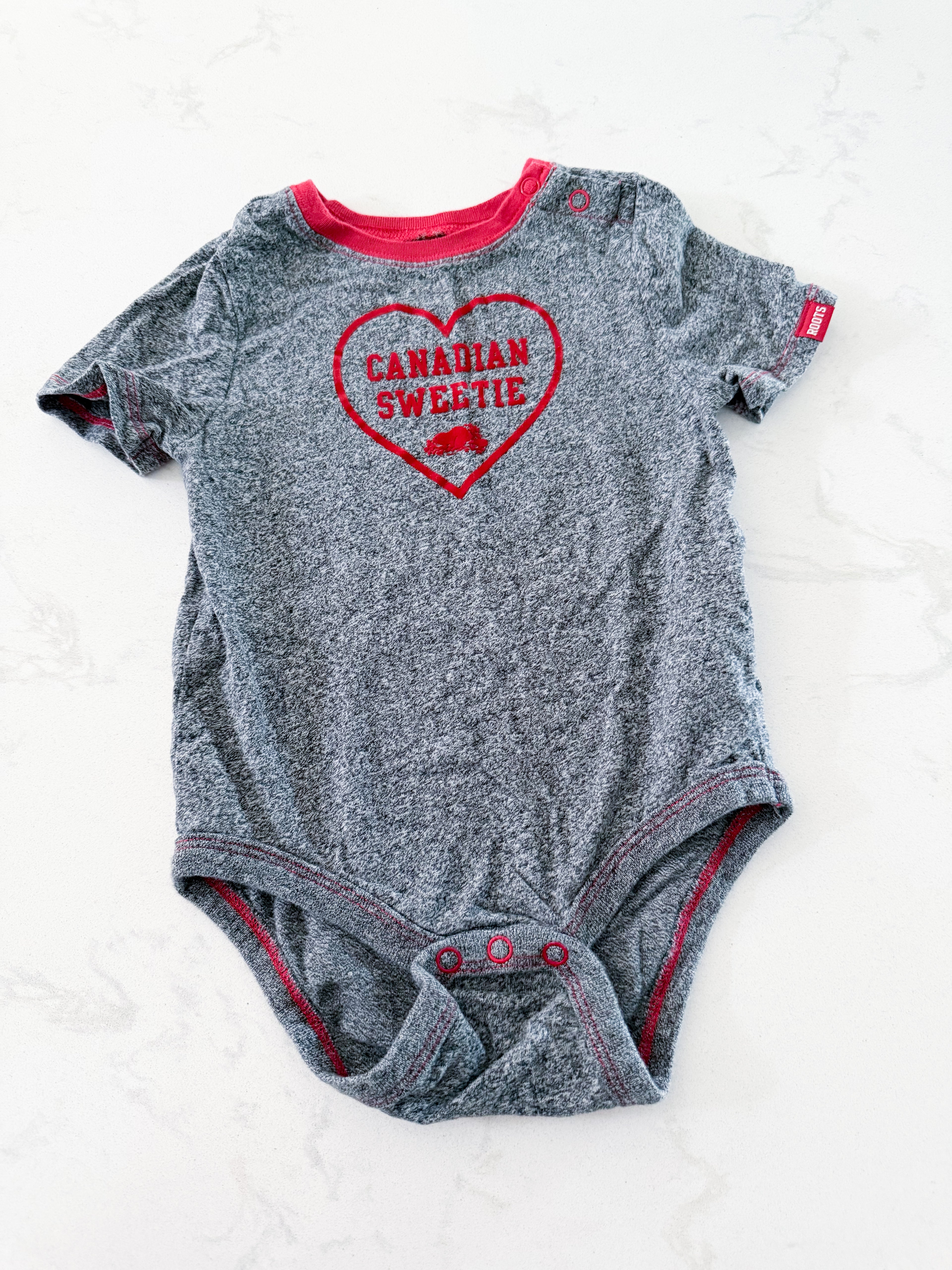 Roots- 18-24m- VGUC- grey speckled short sleeve bodysuit with Canadian sweetie on front