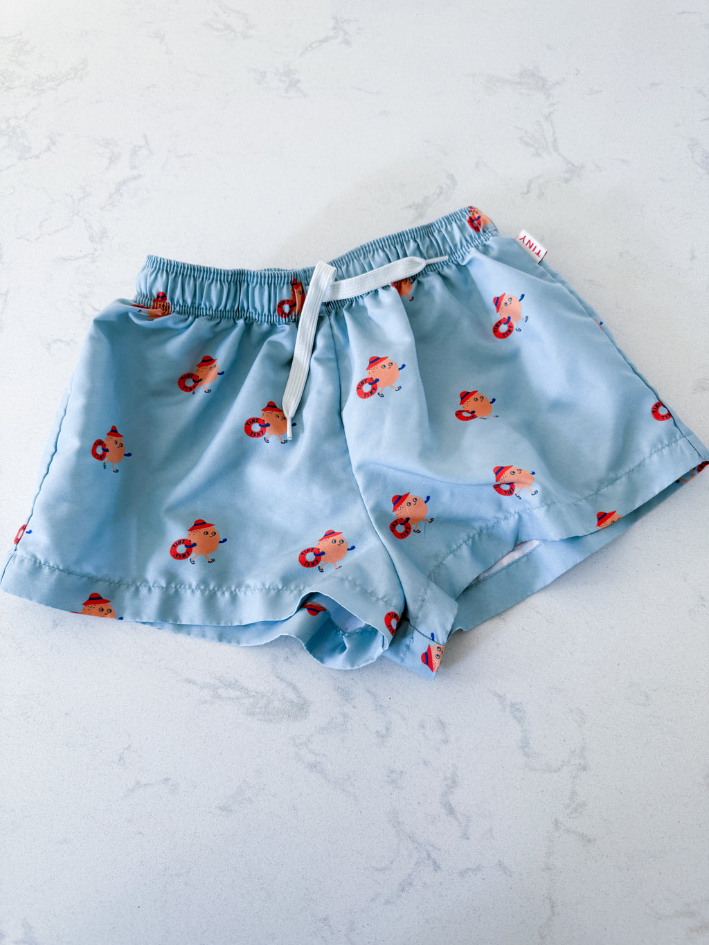 Tiny Cottons- fits 5T- VGUC- light blue swim trunks with orange cartoon graphic