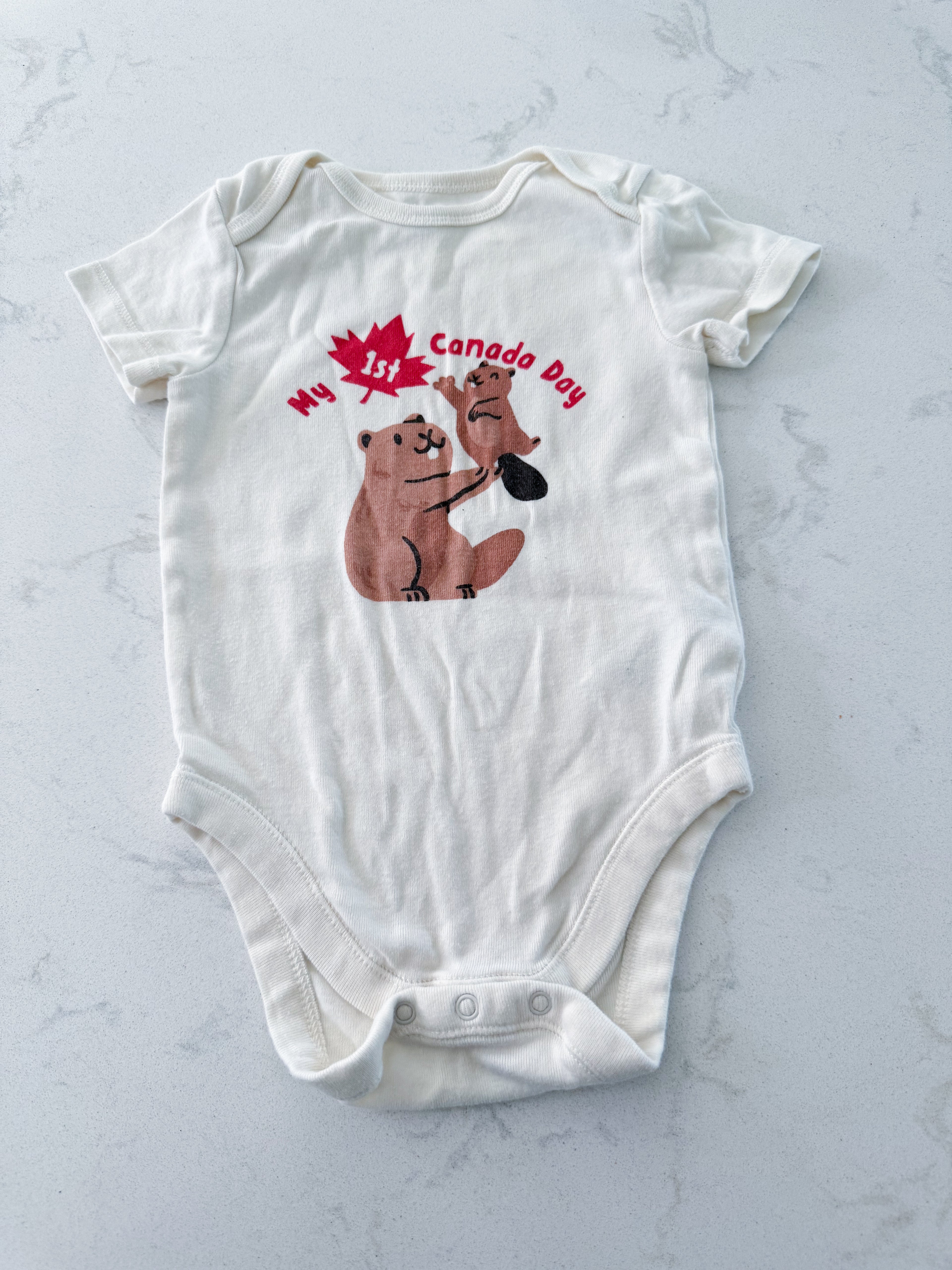 Old Navy- 6-12m- VGUC- cream coloured short sleeve bodysuit with “my 1st Canada Day” and beaver graphic