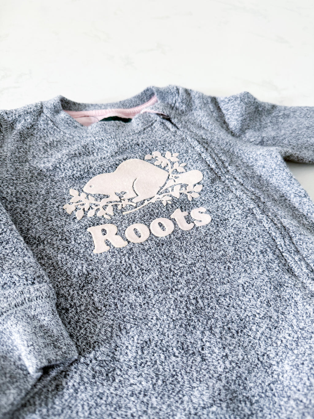 Roots- 6-12m- GUC- Grey speckled one piece sweat suit with pink logo