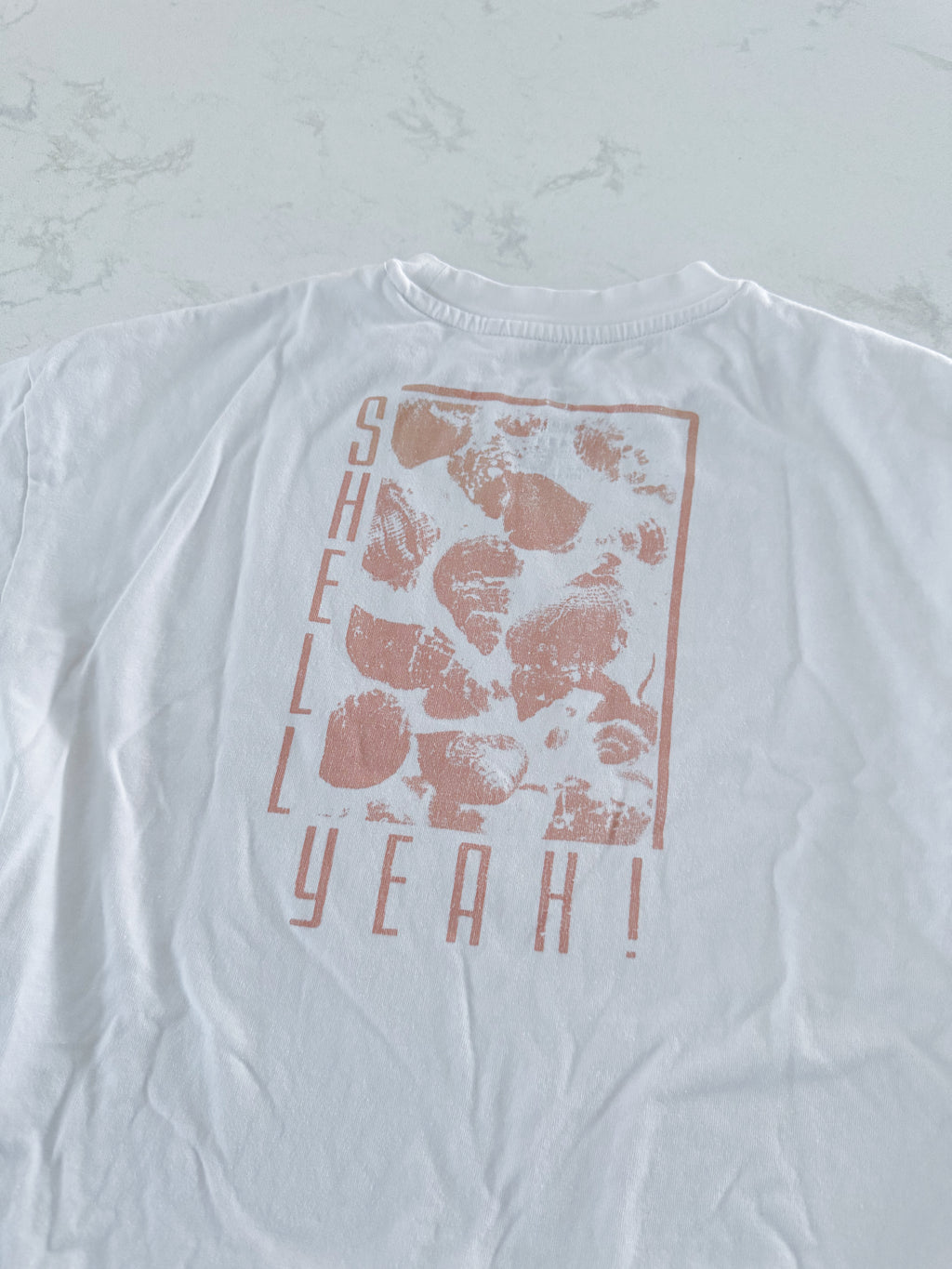 Tag- 10Y- VGUC- white short sleeve t shirt with “shell yeah” in beige