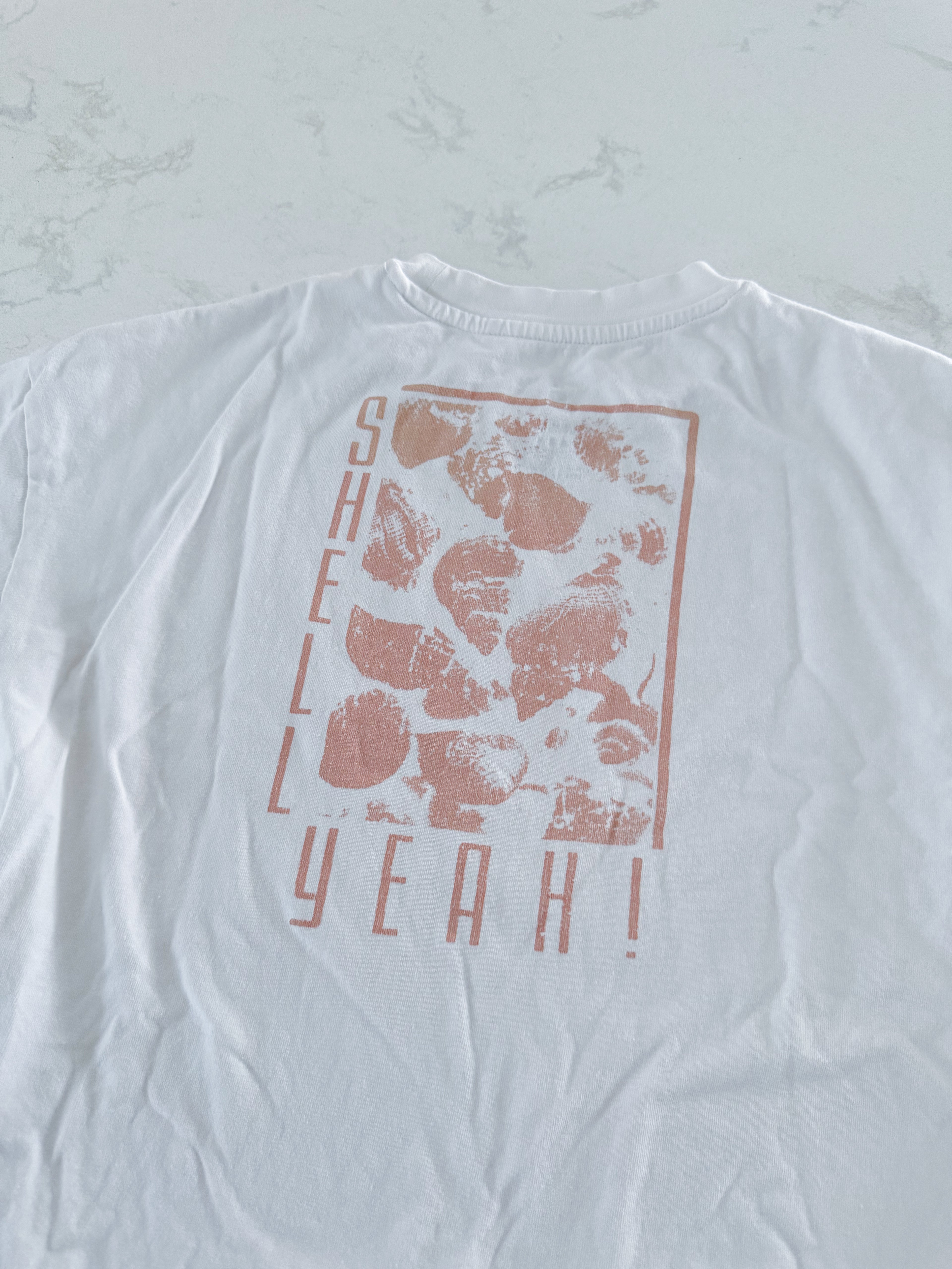 Tag- 10Y- VGUC- white short sleeve t shirt with “shell yeah” in beige