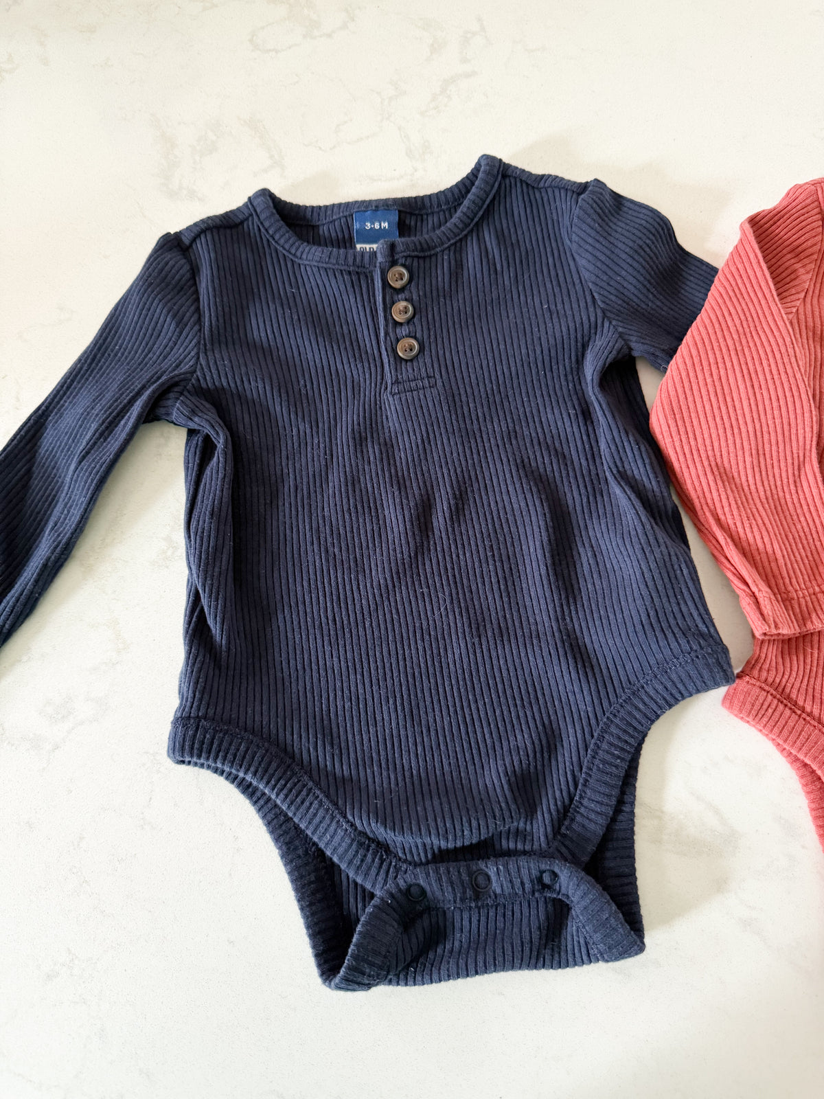 Old Navy- 3-6m- VGUC- two long sleeve ribbed bodysuits, navy and terracotta colouring