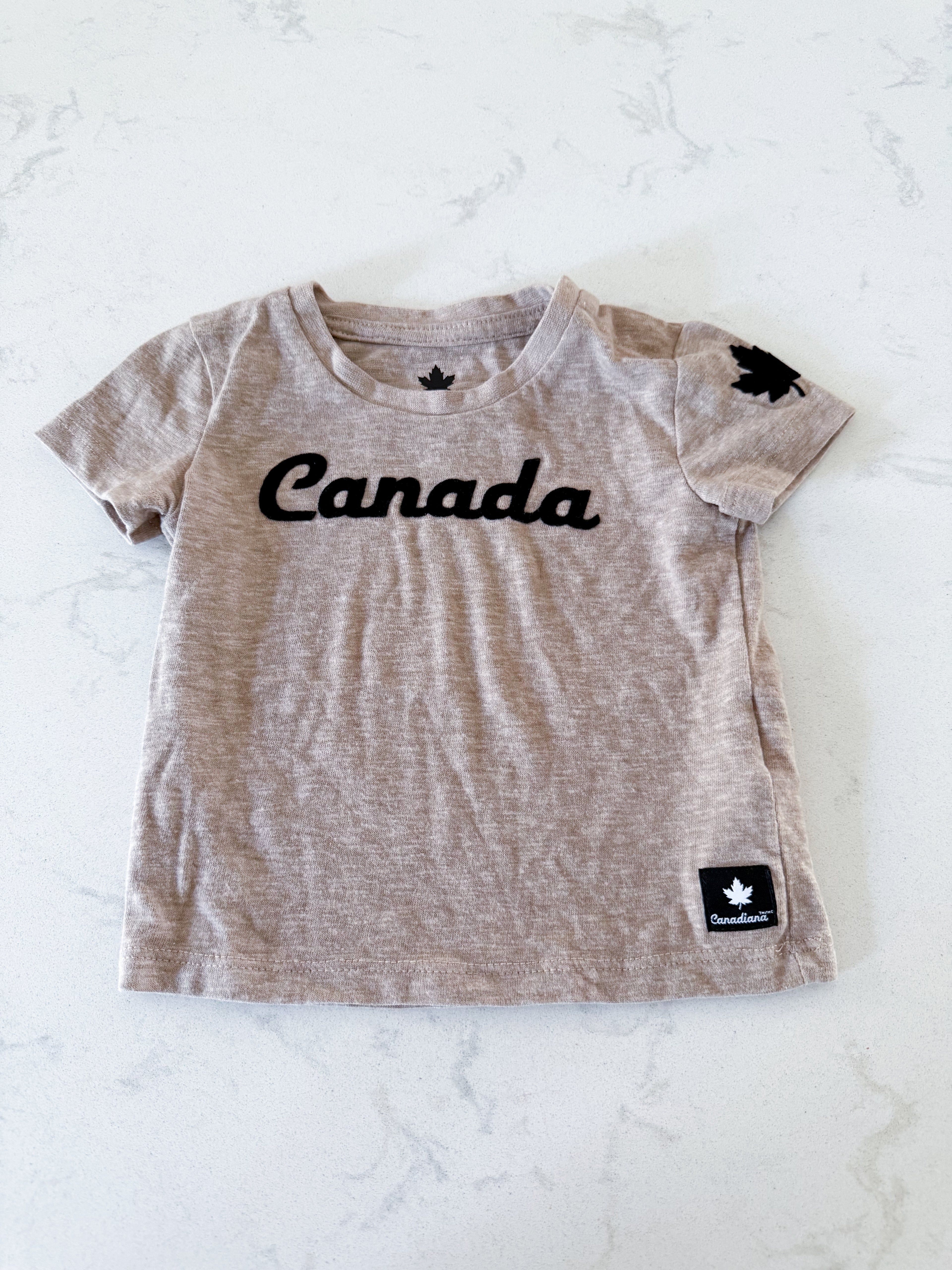 Canadiana- 3-6m- VGUC- beige t shirt with black velvet lettering
