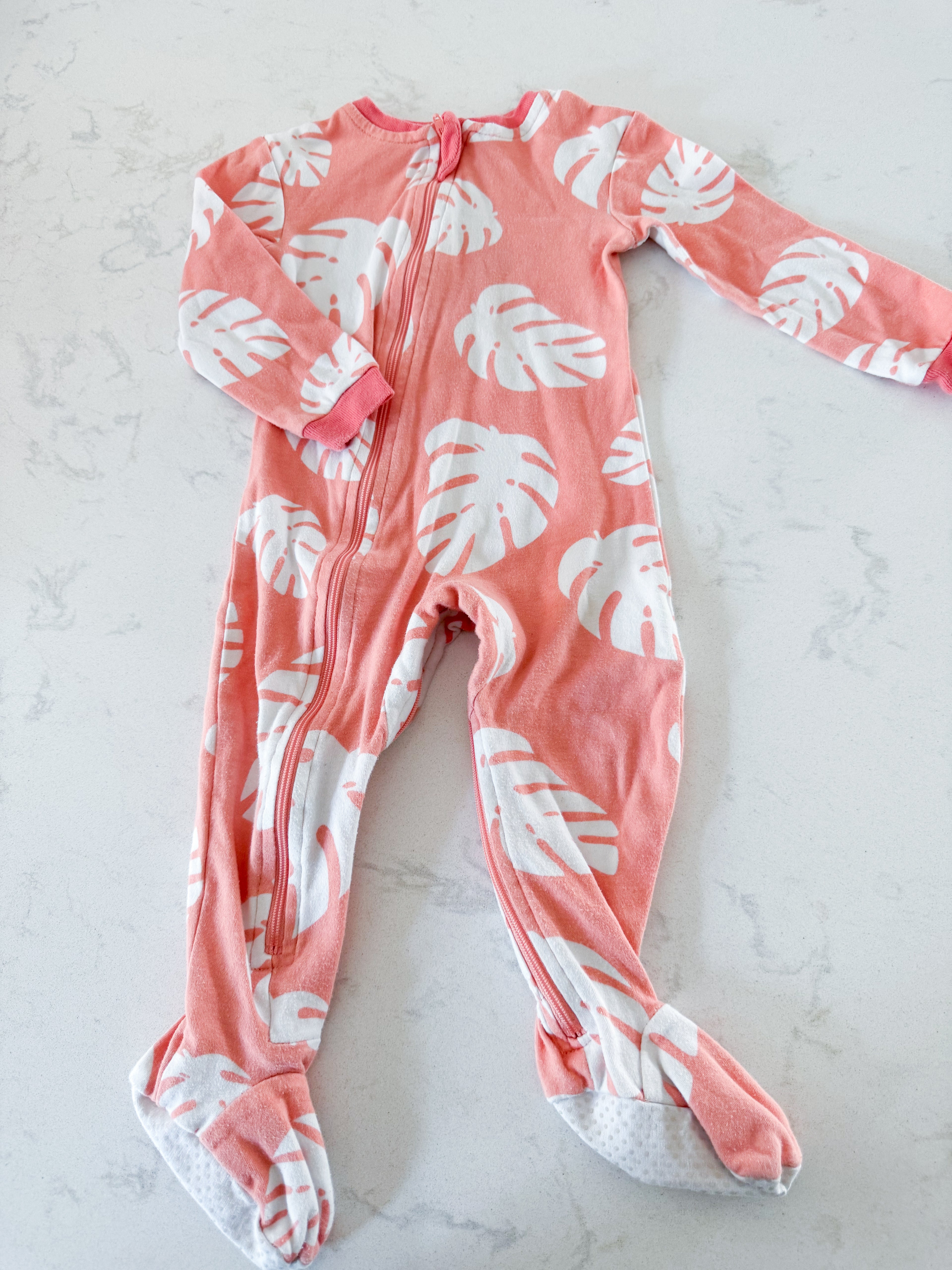 Zippy Jamz- 9-12m- PLAY- orangey pink zip up jammies with white tropical leaves