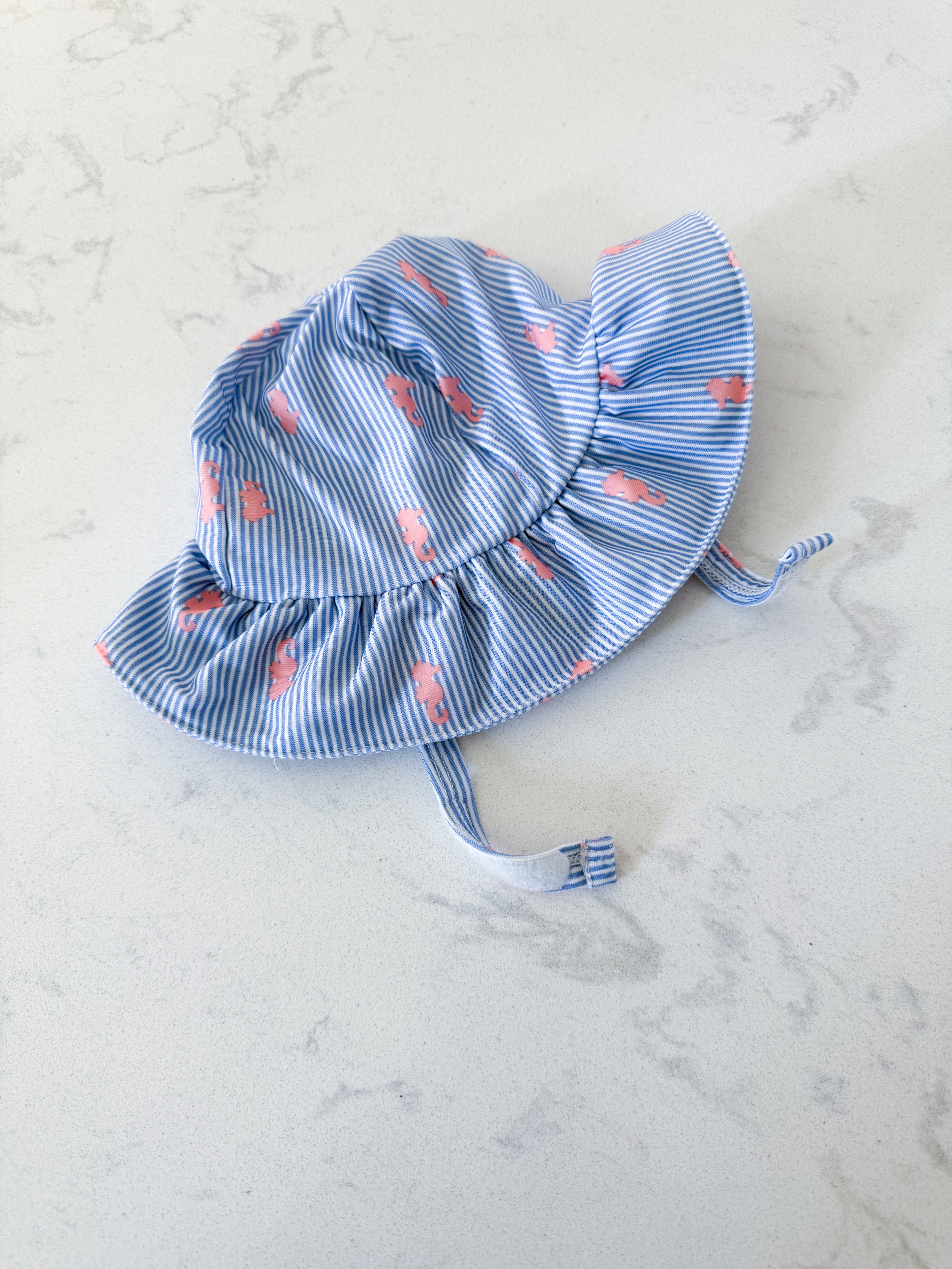Gymboree- 6-12m- VGUC- swim hat with blue and white stripes and pink seahorses