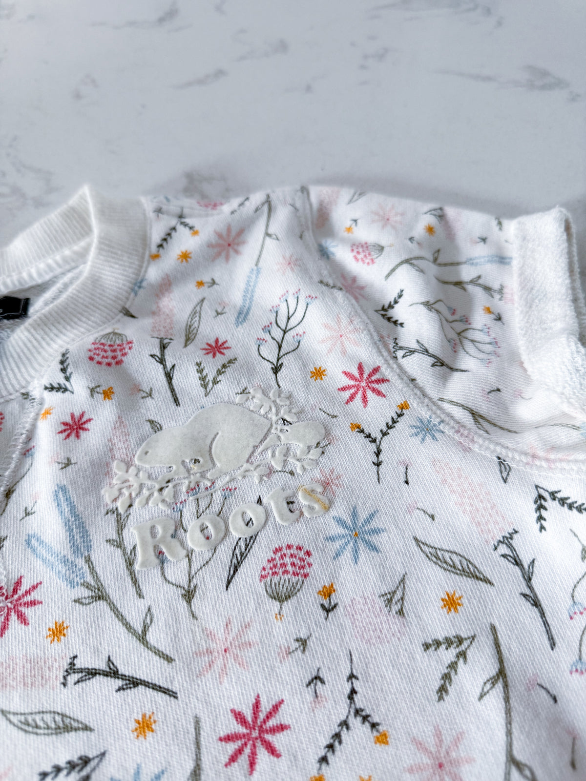 Roots- 9-10Y- VGUC- White short sleeve sweater dress with multicoloured wildflower pattern and white Roots logo