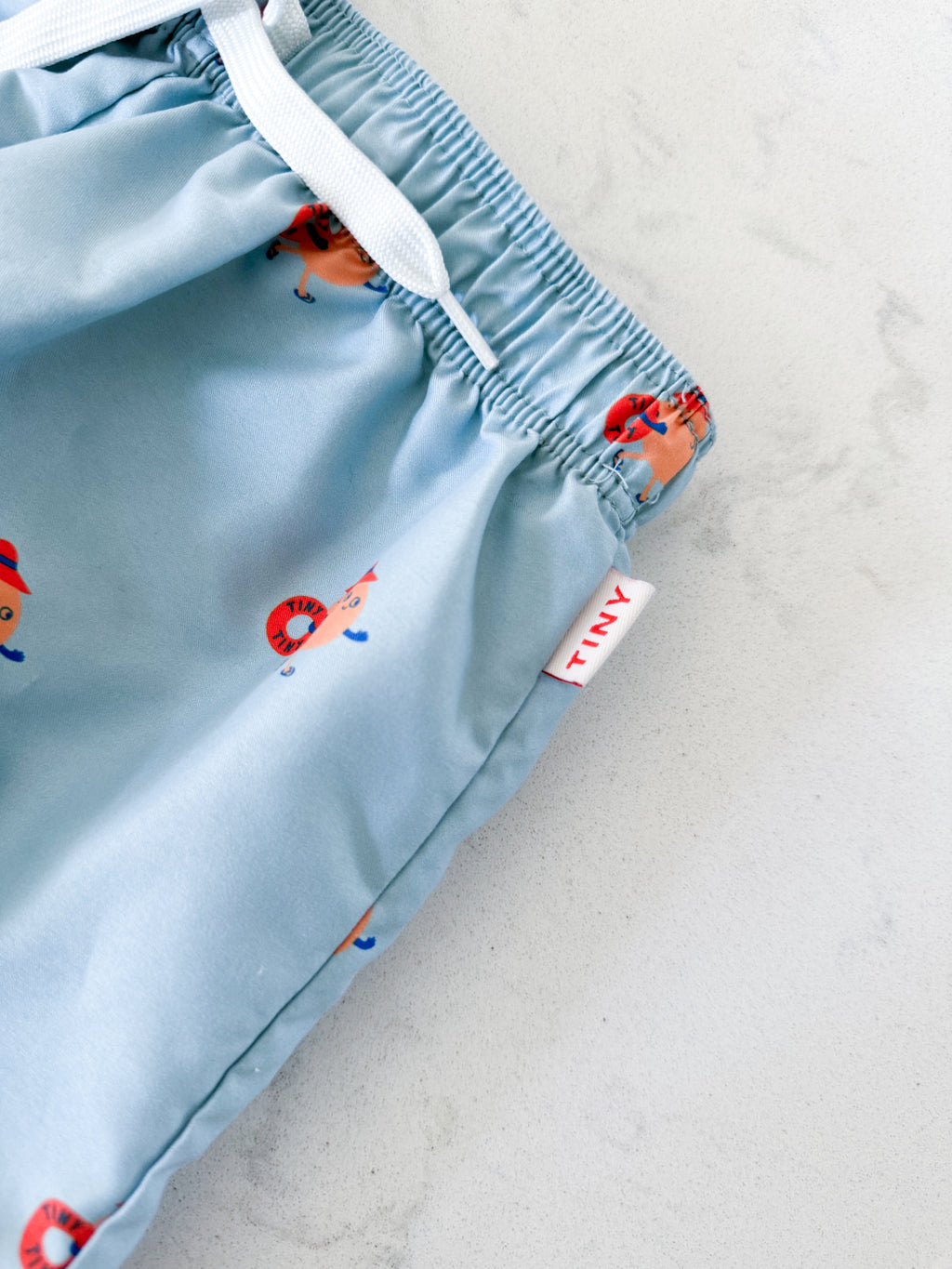 Tiny Cottons- fits 5T- VGUC- light blue swim trunks with orange cartoon graphic