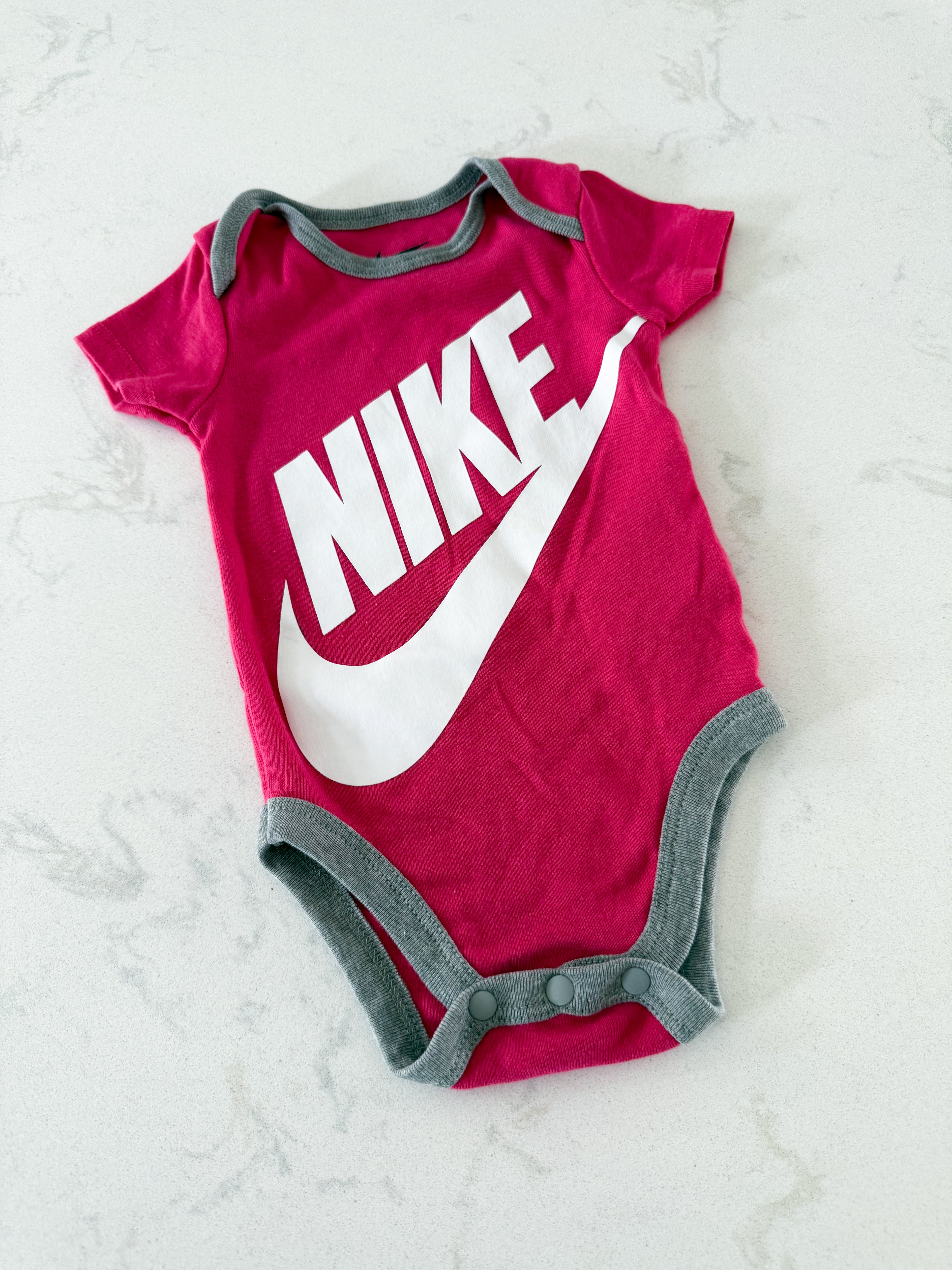 Nike- 0-3m- GUC- pink short sleeve bodysuit with white logo and grey trim